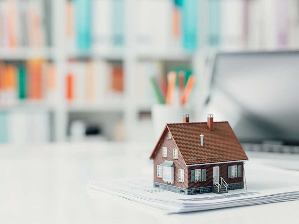 A couple reviews paperwork together at a kitchen table, focusing on financial documents and a laptop.