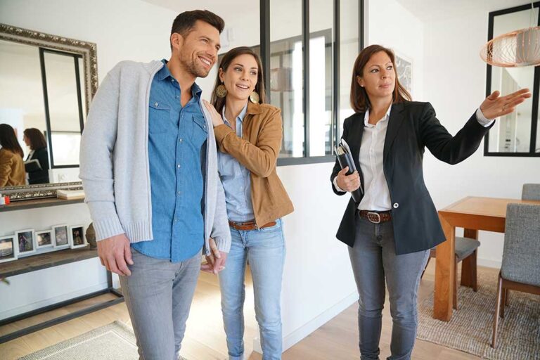 Two people review a home inspection checklist in the kitchen of a house during daylight.